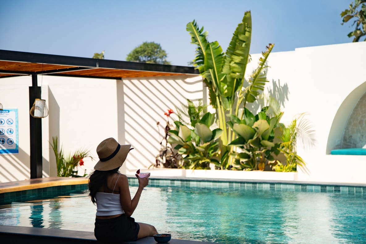 A guest sitting by the pool at Emerald Lotus Villas, surrounded by tropical planting