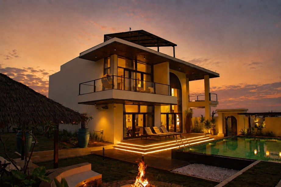 Emerald Lotus Villas at dusk, with a lit pool, firepit and double-height balcony